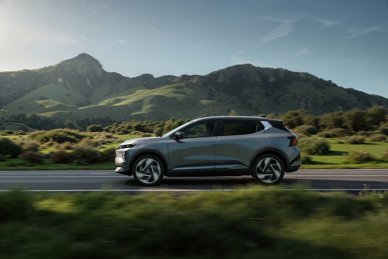 Eclipse Cross EV de perfil, em andamento numa estrada com montanhas verdes ao fundo