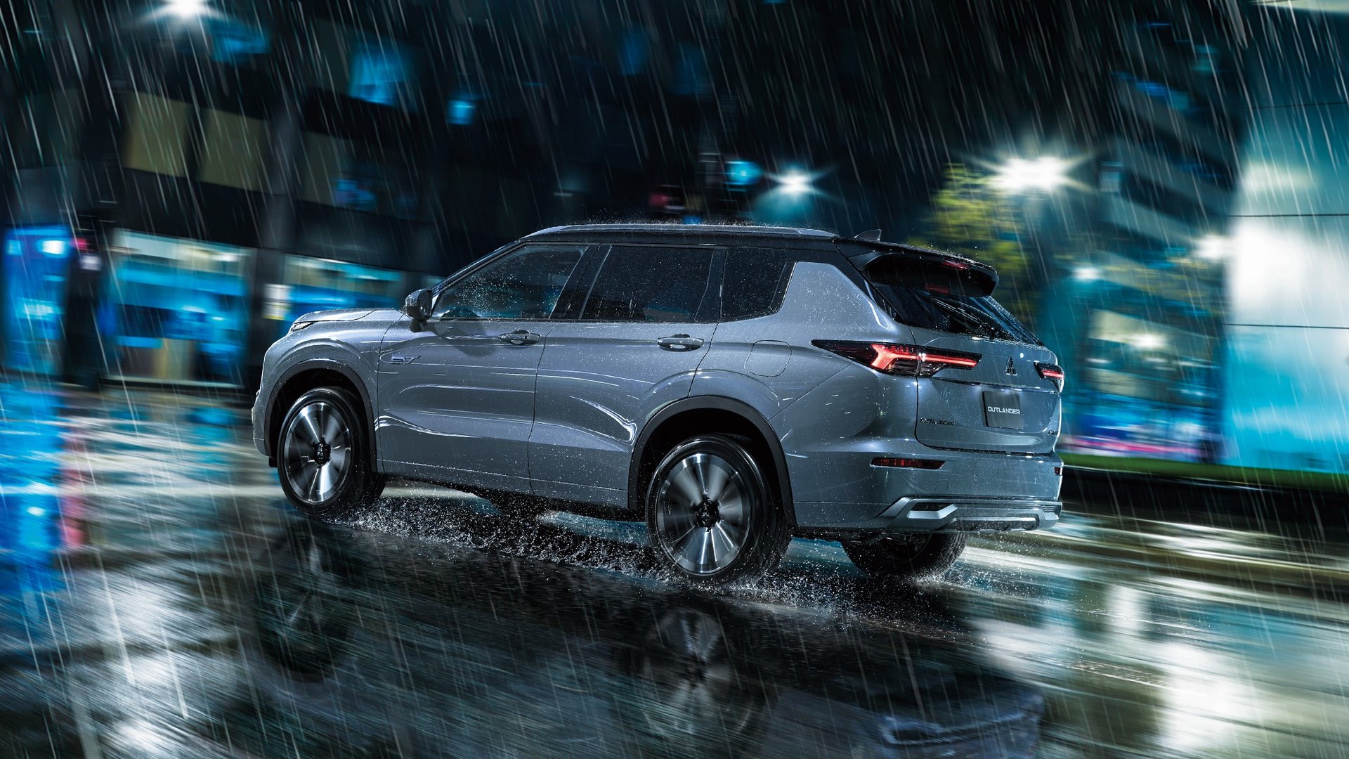 Mitsubishi Outlander PHEV numa avenida molhada, à noite, com as luzes da cidade desfocadas atrás