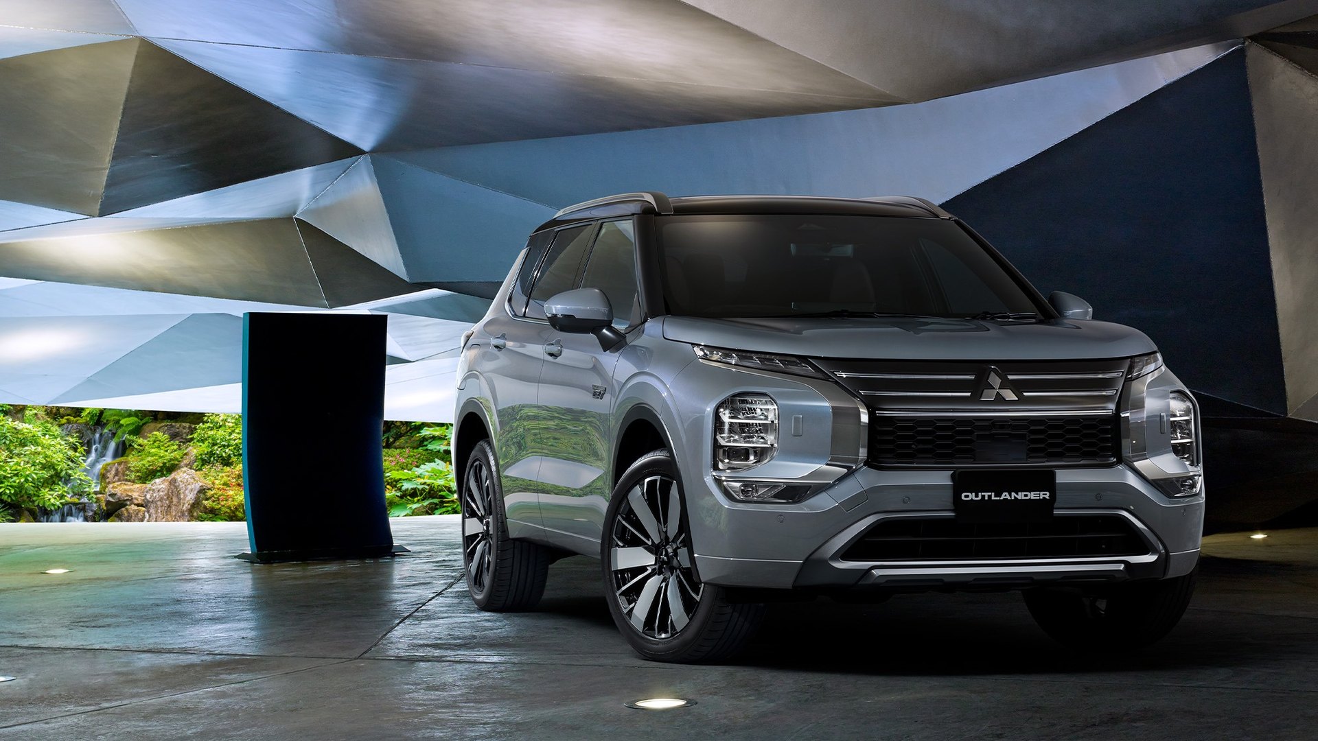Mitsubishi Outlander PHEV prateado visto de frente, três quartos, num pavilhão de painéis metálicos