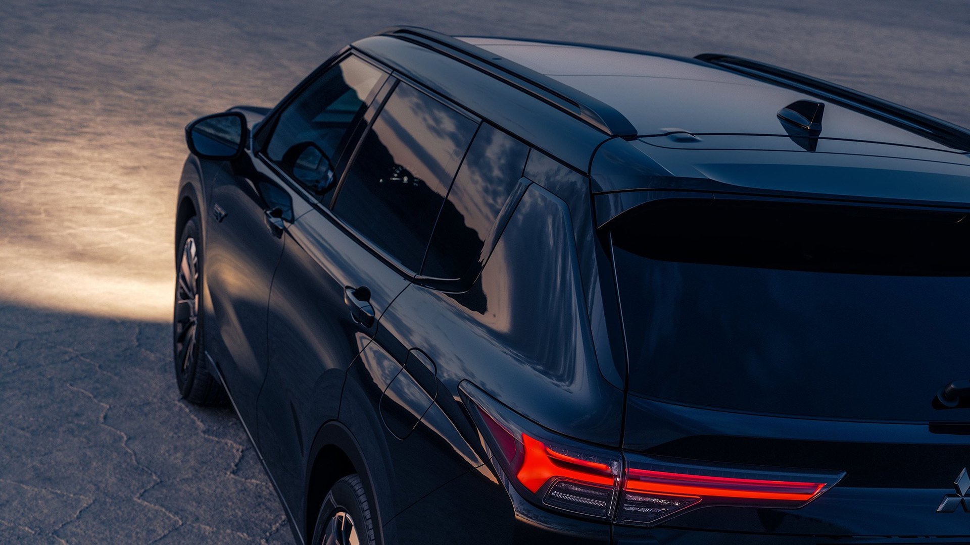 Pormenor do tejadilho e do farolim traseiro de um Mitsubishi Outlander PHEV preto, visto de cima