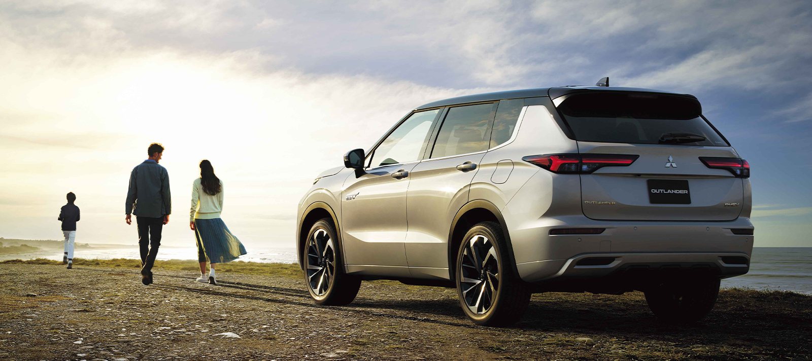Uma família a afastar-se do Mitsubishi Outlander PHEV ao fim da tarde